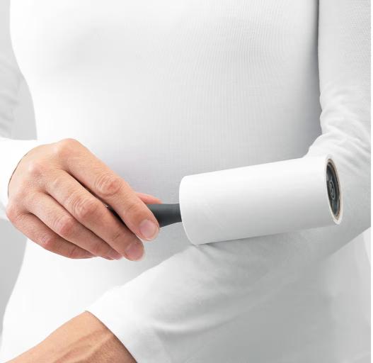 Person using a white roller on their arm with a plain background
